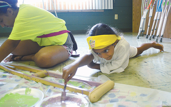 Layla Hassen , 8, helps paint a crutch during vacation Bible school this week at Disciples Christian Church in Boardman. The church’s VBS focused on performing acts of kindness for neighbors near and far.