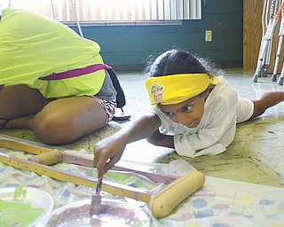 Layla Hassen , 8, helps paint a crutch during vacation Bible school this week at Disciples Christian Church in Boardman. The church’s VBS focused on performing acts of kindness for neighbors near and far.