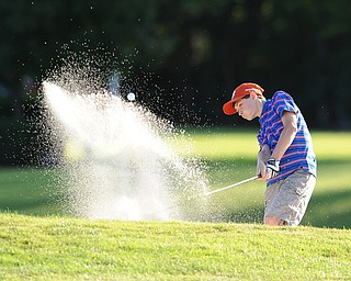 Tavish Burd chips his ball out of the sand trap and onto the green on the 18th hole Sunday afternoon at Trumbull Country Club.