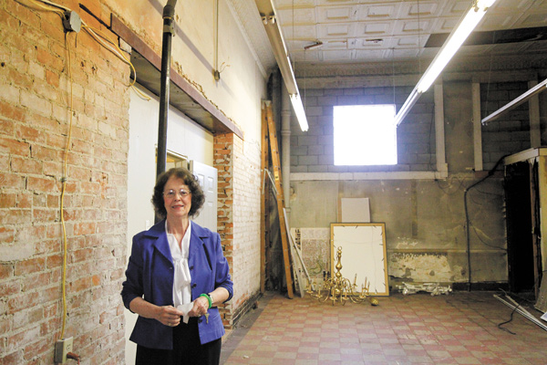 Pat Galgozy, executive director of Trumbull Art Gallery, shows off the brickwork and tin ceiling at the gallery’s new location on North Park Avenue in downtown Warren.