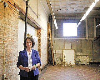 Pat Galgozy, executive director of Trumbull Art Gallery, shows off the brickwork and tin ceiling at the gallery’s new location on North Park Avenue in downtown Warren.