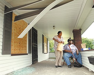 Wanda and John Mack sit on the porch of their 539 Cohasset Drive home Thursday, the day after it was heavily damaged when the house next door exploded. They are putting in a claim with their insurance company and are staying at a hotel until the damaged is fixed.