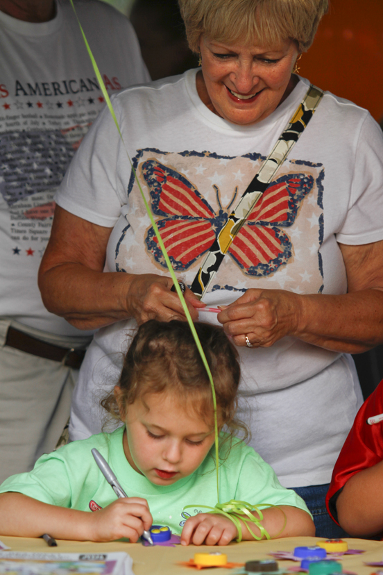 MADELYN P. HASTINGS | THE VINDICATOR..Diane Barnett of Austintown watches her granddaughter Savannah Cervone, 5, make a craft at the Austintown National Night Out in the Austintown Township Park on August 6, 2013. This is the first year Austintown participated in the National Night Out hosted by the police department and the trustees. .... - -30-..
