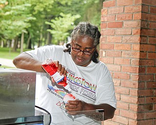 MADELYN P. HASTINGS | THE VINDICATOR..Anita Davis of Youngstown tops off a snowcone with flavor at the Youngstown National Night Out at Wick Park on August 6, 2013. This is part of National Night Out program, dedicated to the development and promotion of various crime-prevention programs including neighborhood watch groups, law enforcement agencies, state and regional crime prevention associations, businesses, civic groups, and individuals, devoted to safer communities..... - -30-..