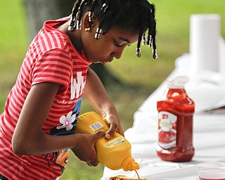 MADELYN P. HASTINGS | THE VINDICATOR..Seairra Brady, 6, of Youngstown tops her hot dog with mustard at the Youngstown National Night Out at Wick Park on August 6, 2013. This is part of National Night Out program, dedicated to the development and promotion of various crime-prevention programs including neighborhood watch groups, law enforcement agencies, state and regional crime prevention associations, businesses, civic groups, and individuals, devoted to safer communities.... - -30-..