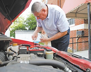 Pastor Ron Maurer of First Christian Church, 140 E. Broadway, Girard, pours windshield wiper fluid into a car just as he will be doing during Inasmuch Day from 10 a.m. to 1 p.m. Saturday. The pastor and a couple of other men from the church will check fluids in cars as part of their day of community service.