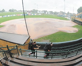 Canfield players Ally Sammarco, left, and Jenna Gibson, right, sprint for cover from a downpour that postponed their game Wednesday at Firestone Stadium in Akron.