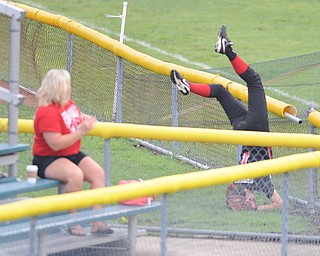 Canfield left fielder #1 Bridget Sweeney tumbles over the short left field wall after attempting to catch a ball in foul territory during Thursday morning game against Michigan. 