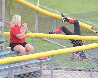 Canfield left fielder #1 Bridget Sweeney tumbles over the short left field wall after attempting to catch a ball in foul territory during Thursday morning game against Michigan. 