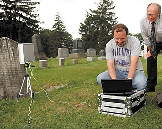 Matt O’Mansky, left, a Youngstown State University associate professor, and Jerry Ward look at the results of a scan from the eroded tombstone of George Foulkes. O’Mansky is using the scanner to try to make out the words on the tombstone in Glenview Cemetery in East Palestine.