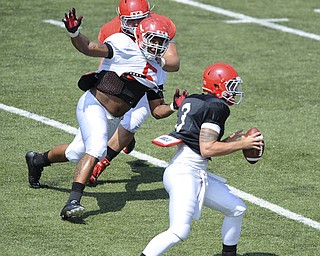 Youngstown State defensive linemen #5 Vince Coleman applies pressure to quarterback #3 Dante Nania after beating offensive linemen #61 Justin Spencer off the ball during a scrimmage on August 10, 2013.