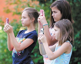 A historic moment is captured by students and neighbors Sarah Barriner, 10, left, Hannah Antal, 10, and Hayley Antal, 8, as they each took a picture of the Idaho Road ribbon-cutting Monday with their cellphones.