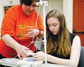 Karen Saunders, assistant supervisor of children’s work, teaches Megan Banks, 16, of Boardman how to use a knitting machine at the Boardman branch of the Public Library of Youngstown and Mahoning County. The demonstration was part of the library’s “Show What You Know” program.