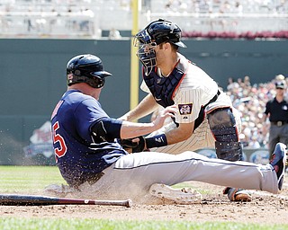 The Indians’ Jason Giambi slides by Twins catcher Joe Mauer to score on a two-run single by Mike Aviles in the fourth inning of Wednesday’s game in Minneapolis. Giambi connected for a three-run homer in the eighth, and
Michael Bourn hit a sacrifice fly in the 12th to give the Indians the 9-8 win. Mauer tied a career high with five hits for Minnesota.