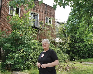 Jan Pentz of Youngstown’s North Side stands in front of two houses on the 1300 block of Wick Avenue that are in need of demolition. Pentz lives across the street from the structures.
