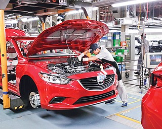 A Mazda employee works on the assembly line at the plant in Hofu, Yamaguchi Prefecture, southwestern Japan, on Tuesday. Mazda, the longtime also-ran of Japanese automakers, has a new super-efficient plant that’s rolling off vehicles at a stunning rate of one every 54 seconds.