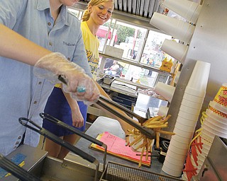 Vindicator reporter Kalea Hall tries her hand at cooking french fries at a Molnar’s stand at the Canfield Fair. Molnar’s has 12 concession stands and has been at the fair for 45 years.