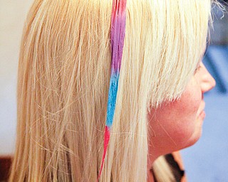 Wrobel’s blond hair is highlighted with bright colors after Myers applied special chalk to it. The temporary color can be used on strands of hair from crown to ends or just on the tips of hair.