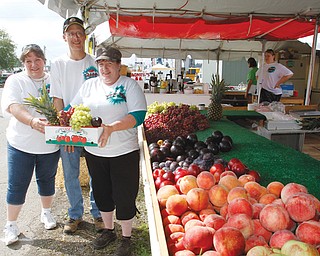 One of the staples at the Canfield Fair is Guzzo’s Fruit Stand on Bishop Street. Showing off some of the produce fairgoers can buy are, from left, Christina Guzzo, Bill Welsh and Ella Maria Guzzo-Welsh.