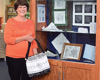 Kathie Sabatino of Salem stands next to a display of Zentangle-inspired designs, including a purse she made, at Leetonia Community Public Library. She off ered classes at the library on the unique form of expression that has a meditative quality. Sabatino, who operates The Sewing Room, said the Zentangle art form helped improve her quilting. At top, a close-up view shows how she transferred a design to make a purse. The strokes on paper show how a series of lines and other forms combine to make a unique pattern.