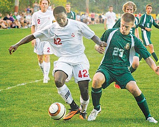 Cardinal Mooney’s Justin Parkins (42) runs with the ball while Ursuline’s Justin Oaks (23) attempts to steal it during a match Tuesday at the James Simon Sr. Soccer Park in Struthers. The Cardinals beat the Fighting Irish, 2-0.