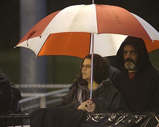 Lynn, left, and Randy Beatty, from Lowellville, try to stay dry Friday night while watching the Rockets at Springfield High School.