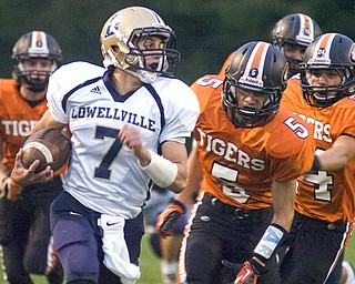 Kelli Cardinal/The Vindicator .Lowellville junior Phil Ginnis carries the ball Friday night against Springfield's Jake Ohlin, center, and other defenders at Springfield High School.