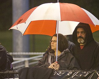 Lynn, left, and Randy Beatty, from Lowellville, try to stay dry Friday night while watching the Rockets at Springfield High School.