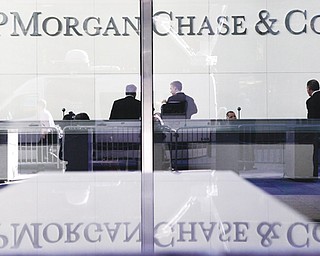 People stand in the lobby of JPMorgan Chase headquarters in New York. The bank will pay $920 million and must admit that it failed to oversee trading that led to a $6 billion loss.