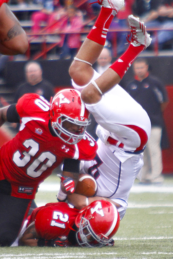 MADELYN P. HASTINGS | THE VINDICATOR..Duquesne's Carter Gianni (2) flips over YSU's John Medina (30) and Dale Peterman (21) during their game at Stambaugh Stadium on Saturday, September 21. .... - -30-..