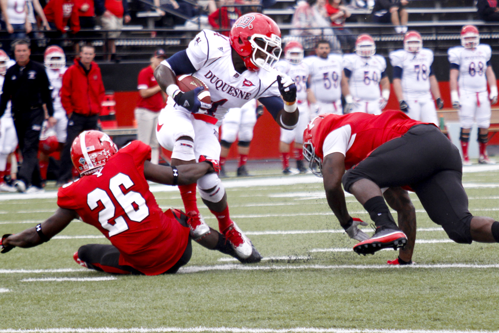 MADELYN P. HASTINGS | THE VINDICATOR..YSU's Jameel Smith (26) pulls Duquesne's Chris Johnson (4) down to the ground while YSU's Adaris Bellamy (13) looks on during their game at Stambaugh Stadium on Saturday, September 21. ... - -30-..
