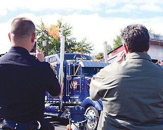 Police officer D.J. Aldish, left, and Donny Bovo, both of Struthers, take pictures of the flames and smoke coming from a truck at the Show with a Cop car show in Struthers on Sunday. Bovo said he came out to see some of his friends and to give a donation to the charity. Proceeds from the event go toward the Struthers Shop with a Cop program in which children from low-income families are given $100 each and taken shopping with officers to brighten their Christmas.