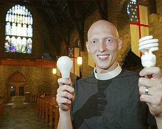 Rev. Jeremiah Williamson, assistant pastor at St. John Episcopal Church in Youngstown holds an incandesant buld in one hand and a flourescent in the other. The church is replacing incandesant bulbs with flourescent to save energy. William D. Lewis / The Vindicator