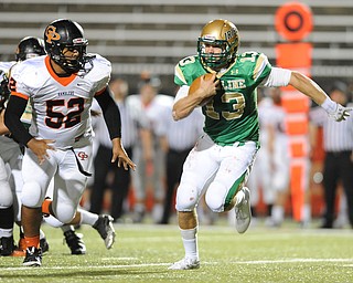Ursuline quarterback #13 Chris Durkin attempts to run away from Cathedral Prep defensive linemen #50 Matthew Wolf. He would be sacked on the play.