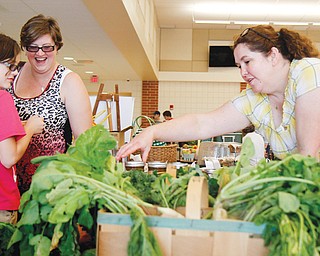 Mackenzie, 10, left, and Courtney Kuhns of Austintown admire the goods at Bridget Harker’s farmers’ market booth set up inside Austintown Intermediate School for the Awesometown event Sunday.
