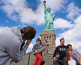 Tourists pose for photographs in front of the Statue of Liberty in New York Harbor on Sunday in New York. The Statue of Liberty reopened to the public after the state of New York agreed to shoulder the costs of running the site during the partial federal-government shutdown.