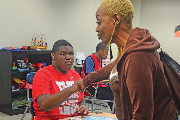 Maurice Castel, 15, fist-bumps his aunt, Bonnie Hunter of Wisconsin, after he finished a lesson at the new Potential Development High School for Autism in Youngstown. Maurice is nonverbal but has shown improvement through the Potential Development program. The non-charter public school for teens in grades nine through 12 on the autism spectrum had a ribbon-cutting Wednesday.