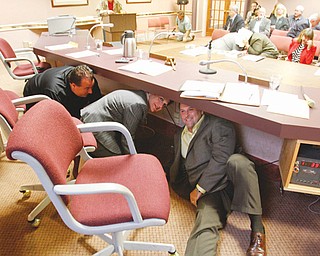 Mahoning County commissioners, from left, Anthony Traficanti, Carol Rimedio-Righetti and David Ditzler, take
cover at 10:17 a.m. Thursday in the midst of their meeting in the basement of the county courthouse. They
took part in a regional earthquake preparedness drill, known as the Great Central U.S. ShakeOut.