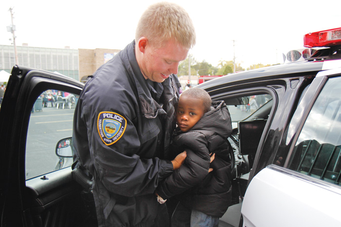 Youngstown State University police officer Mark Menley helps 2- year-old Da’Reion Solomon of Youngstown get out of a police cruiser at the Neighborhood Harvest. The festival was sponsored by ICU Block Watch, St. Dominic Church and Horizon Academy and featured music, treat bags with candy, Kids Identi-Kits and an inflatable
bounce house.
