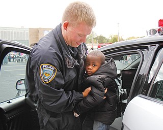 Youngstown State University police officer Mark Menley helps 2- year-old Da’Reion Solomon of Youngstown get out of a police cruiser at the Neighborhood Harvest. The festival was sponsored by ICU Block Watch, St. Dominic Church and Horizon Academy and featured music, treat bags with candy, Kids Identi-Kits and an inflatable
bounce house.