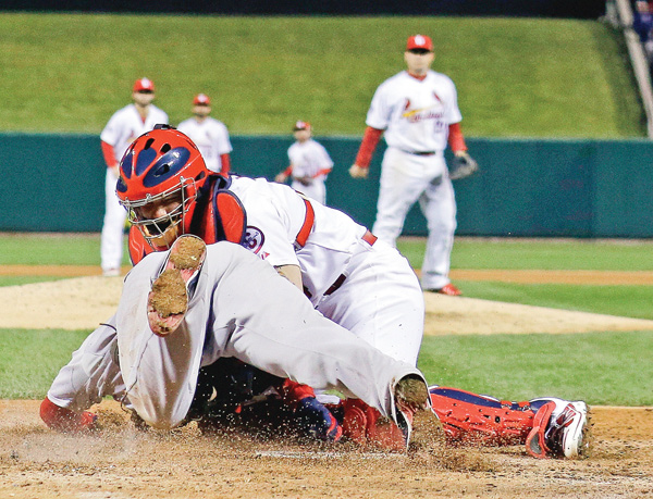 Cardinals catcher Yadier Molina tags out the Red Sox’s David Ross at home after he tried to score from second on a hit by Jacoby Ellsbury during the seventh inning of Game 5 the World Series on Monday at Busch Stadium in
St. Louis. The Red Sox edged the Cardinals, 3-1, and lead the series 3-2.