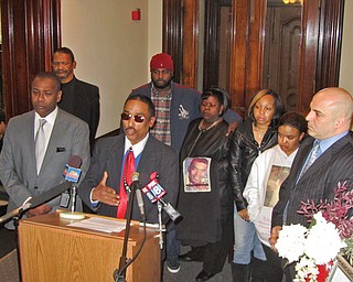 Richard Rollison III, at microphone, addressed the news media Wednesday at Warren City Hall, flanked by Mayor Doug Franklin, left, Warren Safety-Service Director Enzo Cantalamessa, right, and other Rollison family members and friends. Rollison is the father of Richard Rollison IV, 24, who was shot to death Saturday; the father joined in a plea to end further violence in the city.