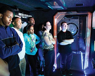 Students at in the Science, Technology, Engineering and Mathematics program at Youngstown’s Chaney Campus, Bryan Moncrief, from left, Omon’dre Moncrief, Sydney McIntyre, Jeremy Woodberry, teacher Carrie Sinkele and Ken Bossick watch a scenario on a screen inside the Army STEM Asset Vehicle, which visited Chaney on Thursday.