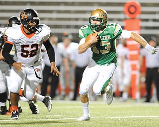 Ursuline quarterback Chris Durkin (13) attempts to run away from Erie Cathedral Prep defensive linemen Devonne Barnes (52) in a game on Sept. 27 at Stambaugh Stadium. He was sacked on the play. The Irish qualified for the state playoff s with a 4-5 record and will play at Akron Manchester (8-2) Saturday.