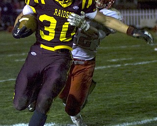Kelli Cardinal/The Vindicator .South Range running back Joe Alessi carries the ball and avoids the tackle by Cuyahoga Heights defender Tyler Gallo during the first half Friday night at Memorial Field in North Lima.
