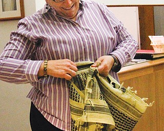Pat Campbell, director of music and worship at Blessed Sacrament Church in Warren, folds a BattleSaint scarf to wear. The church also has the scarves for sale.