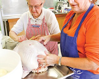 Joyce Rettenmier, left, and Jan Ugran, coordinator with Kathy Longmuir of the turkey dinner at Boardman United Methodist Church, prepare one of 20 turkeys to be roasted. For its annual dinner Thursday, the church will prepare some 427 pounds of turkey.