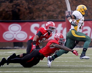 MADELYN P. HASTINGS | THE VINDICATOR..YSU's Tre' Moore (30) and Travis Williams (6) take down NDSU's John Crockett (23) during their game at Stambaugh Stadium on November 16, 2013. The Penguins lost to Bisons 17-35.... - -30-..