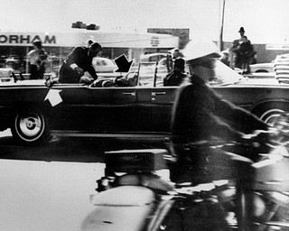 Secret Service agent Clint Hill climbs into the back seat of the limousine a moment after President John F. Kennedy and Governor John Connally of Texas were shot in Dallas, Nov. 22, 1963.  Black arrow points to Mrs. Connally ducking bullets, and white arrow points out the agent's foot, mistakenly thought to be the president's when the photo first ran.  