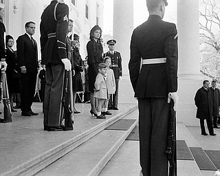 Jacqueline Kennedy and her two children, John Jr. and Caroline stand at the top steps of the Executive Mansion as the body of President John F. Kennedy is carried from the Executive Mansion to lie in state at the Capitol, Nov. 24, 1963. 